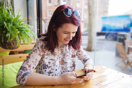 Fotomural Young tourist woman using smartphone in restaurant waiting for her morning coffe