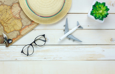 Wall Mural - Top view essential travel items.The  tree map airplane eyeglasses on white  wooden background with copy space.