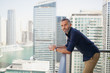 © phocal Media - Expat man with coffee cup at balcony.