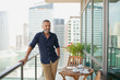 © phocal Media - Expat man standing at balcony.