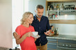 © phocal Media - Couple using mobile at kitchen.