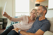 © phocal Media - Couple taking selfie using digital tablet on couch.