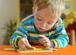 © Sasenki - Little toddler doing puzzle. Boy learns to solve problems and develops cognitive skills and . Child concept.