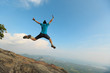 © lzf - successful woman jumping on rocky mountain peak, freedom, risk, challenge, success concept