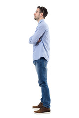 Side view of young businessman with crossed arms looking away. Full body length portrait isolated over white background.