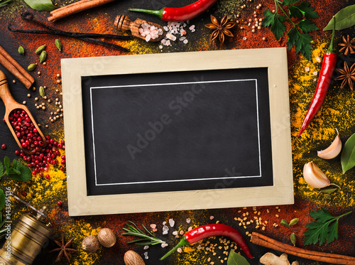 Various spices and herbs surround blank blackboard Canvas Print