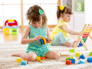Children toddler and preschooler girls play logical toy learning shapes, arithmetic and colors at home or nursery