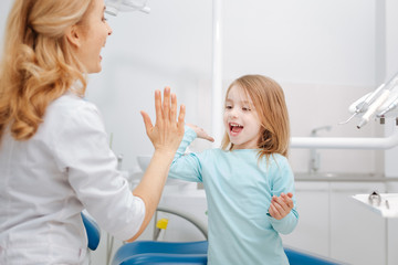 Creative professional dentist giving her little patient a high five