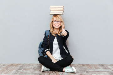Happy young woman student holding books on head.