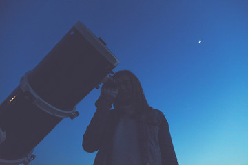 Wall Mural - girl looking at the stars through a telescope.