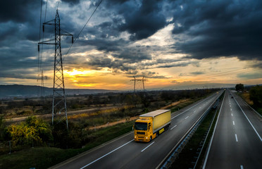 Highway transportation with yellow lorry at sunset