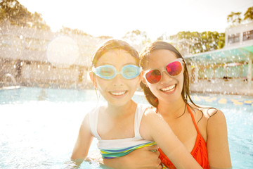 Wall Mural - Happy mother and daughter playing in swimming pool.