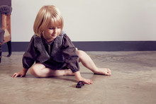 Girl Playing On Floor With Old Wooden Toy Locomotive