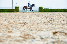Distant View Of Rider Trotting While Training Dressage Horse In Equestrian Arena