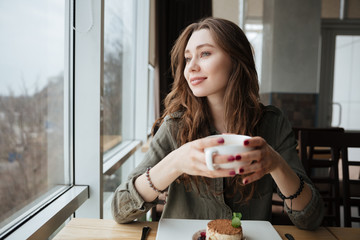 Poster - Happy young pretty lady sitting in cafe drinking tea.