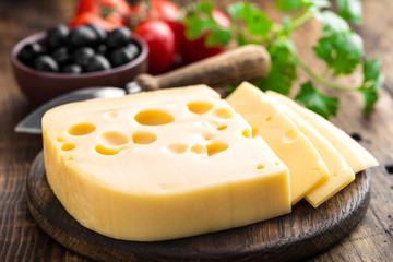 Poster - Delicious Swiss yellow cheese on dark wooden rustic background closeup