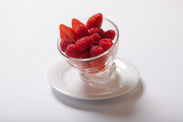 Wall Mural - Ripe sweet raspberries in bowl on white table. Fresh raspberry in a transparent glass plate.