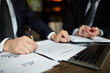 © pressmaster - Closeup portrait of unrecognizable successful businessman wearing black formal suit reviewing documents and signing contract during meeting
