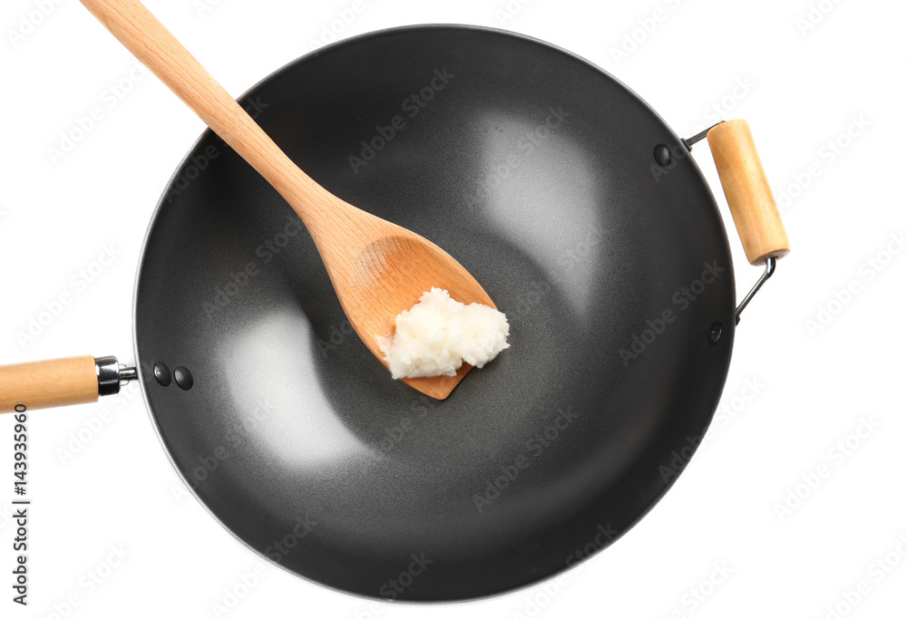 Spatula with coconut oil in wok on white background