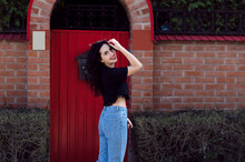 Outdoor Portrait Of Young Beautiful Lady, Red Doors On The Background