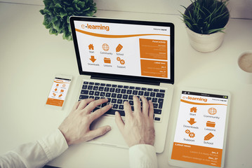 hands writing on a laptop with tablet and phone e-learning