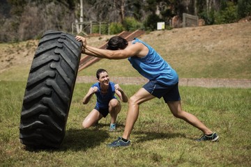 Wall Mural - Fit man flipping a tire while trainer cheering 