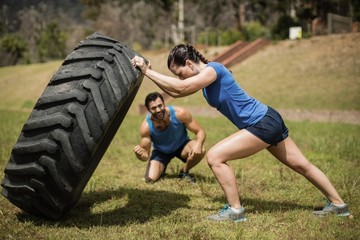 Wall Mural - Fit woman flipping a tire while trainer cheering 