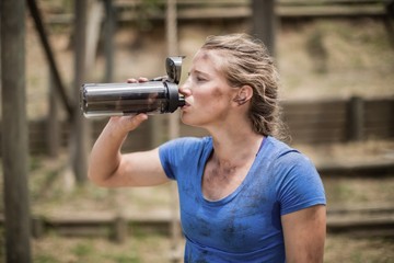 Wall Mural - Woman drinking water from bottle during obstacle course