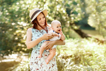 Pretty Young Mother In Hat Holding Newborn Baby Boy, Sunny Summer Spring Nature Background
