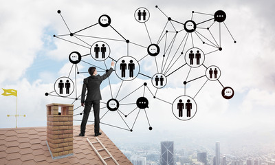 businessman on house roof presenting networking and connection concept. mixed media
