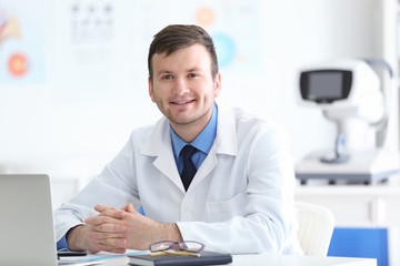 Wall Mural - Young doctor with laptop sitting at table in office