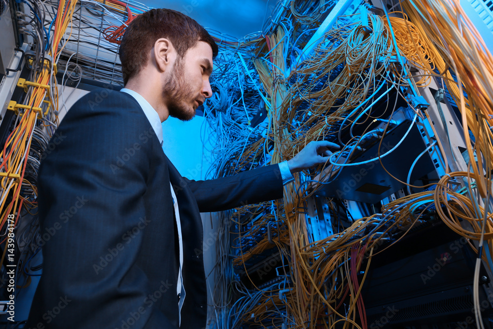 Handsome young engineer working in server room