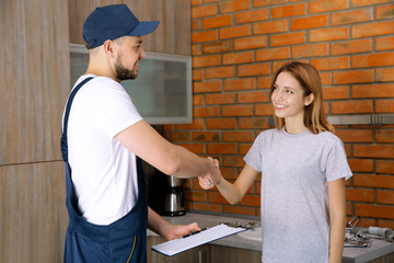 Wall Mural - Plumber and woman shaking hands at home