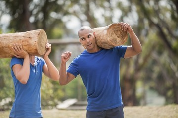 Wall Mural - People carrying heavy wooden logs during obstacle course