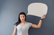 © SokRom - Woman holding a blank field of white copy space shaped like a speech bubble.