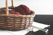 Wool burgundy yarn with needles in wooden basket. Toned photo