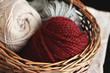 Burgundy, ecru and grey wool yarn in wooden basket