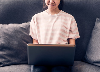 Poster - Young teenage girl sitting in sofa and using laptop computer to study a lesson at home,E-learning concept,vintage filter