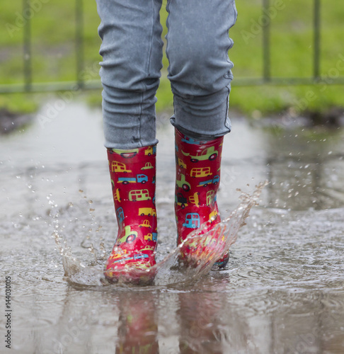 dziecko w kaloszach bawiące się w deszczu - Buy this stock photo and ...