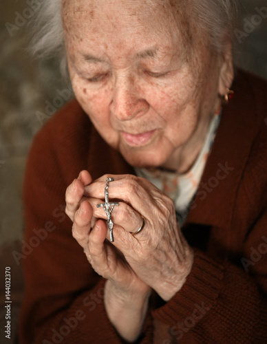 Fotografie, Obraz Old woman praying and holding silver rosary