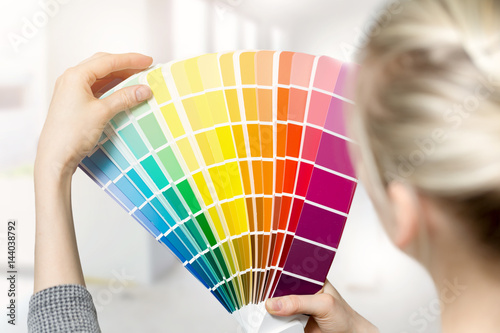 Fotografia Kobieta wybierając kolor farby do wnętrz domu z katalogu swatch