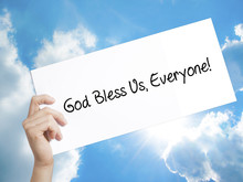God Bless Us, Everyone! Sign On White Paper. Man Hand Holding Paper With Text. Isolated On Sky Background