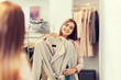 © Syda Productions - happy woman trying coat at clothing store mirror