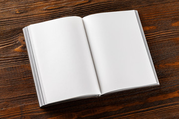 Mockup of opened book with blank pages at wooden table background.