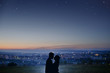 © Parilov - Silhouette of a couple in love against the background of a night city, stars and horizon. Concept is a date on the roof, the first love