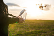 Man operating a drone with remote control. Dark silhouette against colorful sunset.