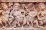 Dancing overweight people on stone relief of 7th century temple in Badami town, India. Famous for rock cut architecture of Karnataka