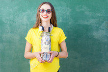 Young And Happy Woman In Yellow T-shirt Holding A Bottle With Money Savings For Study