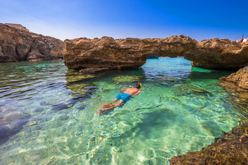 blue lagoon, malta - snorkeling tourist at the caves of the blue lagoon on the island of comino on a