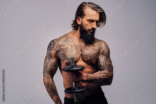 A Man With Long Hair And Tattoo On His Torso Holds Dumbbell Buy